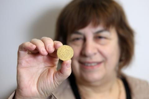 Dame Jenny Abramsky, Chair of NHMF, holding up one of the coins from the Asthall Hoard