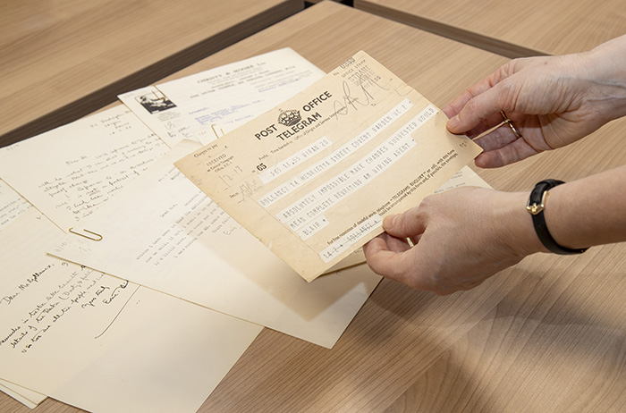 A close up of a person holding a telegram over a pile of archive documents