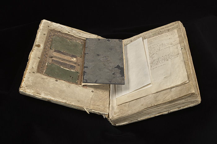 A bound Medieval manuscript open to show a hidden recess in the inside cover
