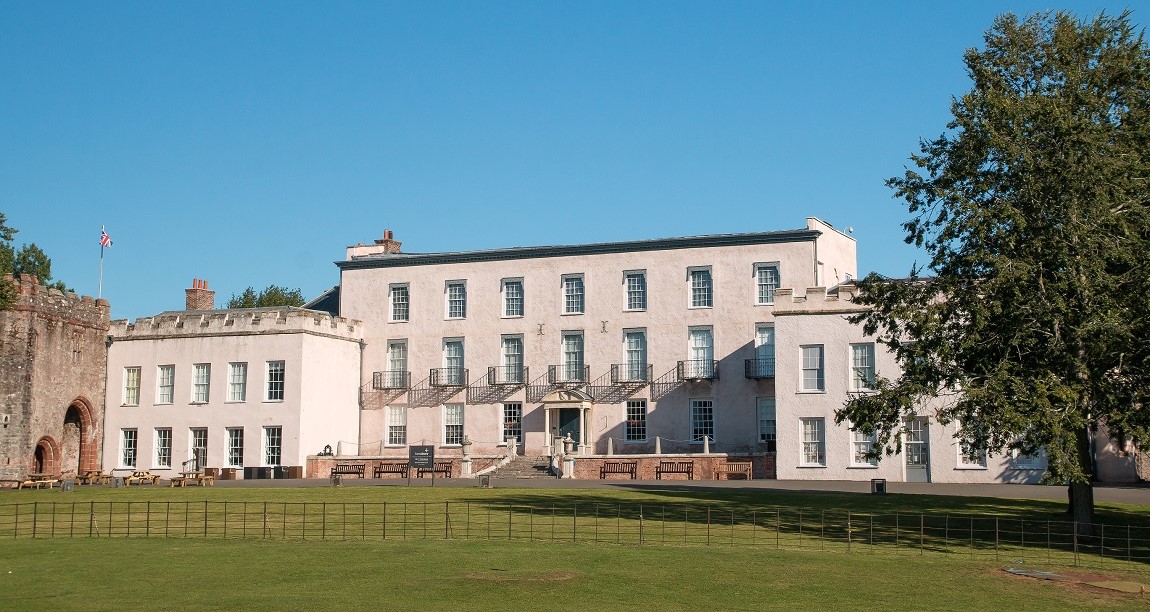 Front-facing view of the abbey on a sunny day. It is a large white building with a lawn in front