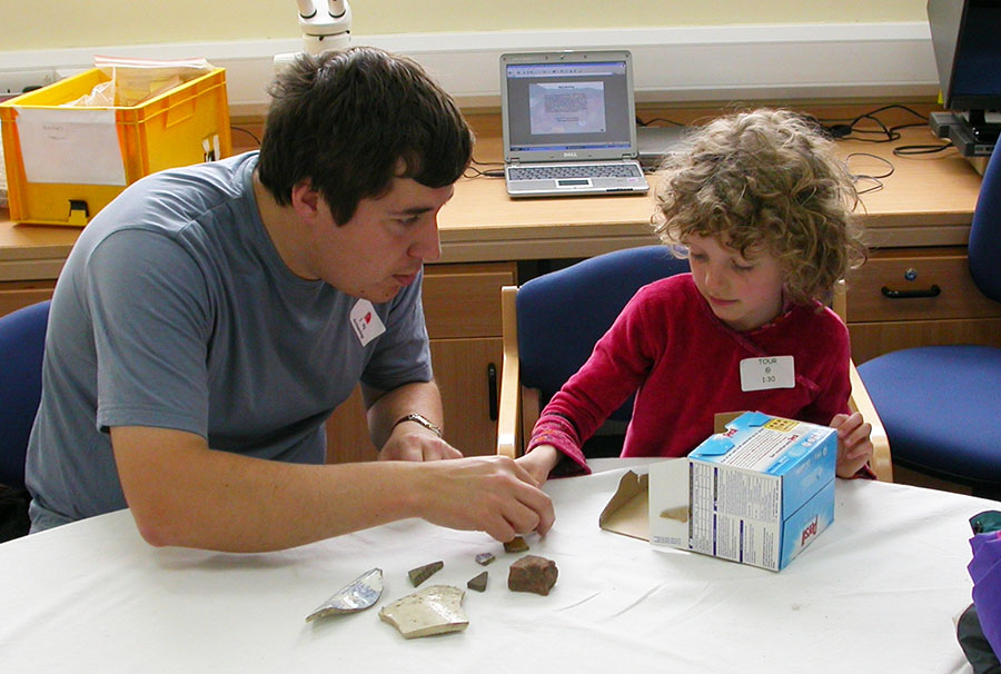 Adult and child look at broken pottery