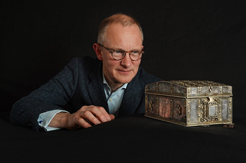 Person looks at small ornate silver casket.