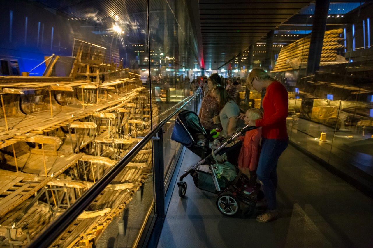 Family look at ship hull through glass pane