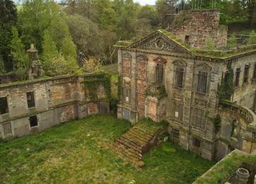 A side view of Mavisbank House showing trees, moss and grass growing inside the building and over the entrance steps