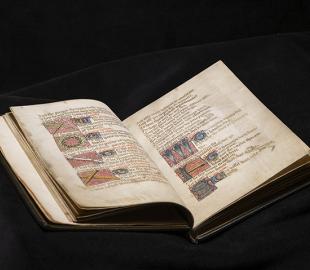 A bound Medieval manuscript open to a page of text illustrated with objects relating to the Passion of Christ